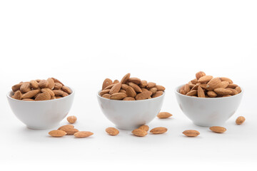 Fototapeta na wymiar small white ramekin bowls filled with almonds on a white background 