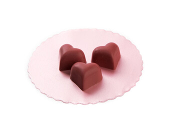 pink valentines strawberry heart shaped chocolates on a pink doily isolated on white