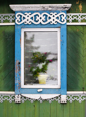 Traditional window with shutters and a flower on the windowsill in a wooden house in Russia