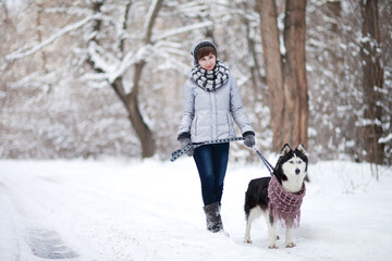 Girl walks with dog siberian husky in winter snowy forest