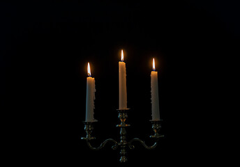 burning candles in candelabra on a black background
