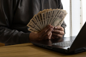 サイバー犯罪でお金を稼ぐ男性のイメージ