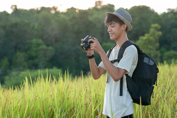 Young Asian traveler photographer on summer wearing knitted hat with backpack looking at  the camera screen