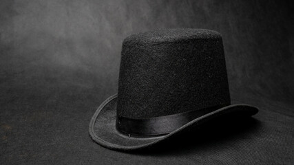 Stylish black bowler hat made of felt on black background.