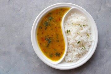 Healthy nutritious Indian comfort food Dal Chawal thali or Dal Rice. Served in two way ceramic plate. Over white background with copy space. - obrazy, fototapety, plakaty
