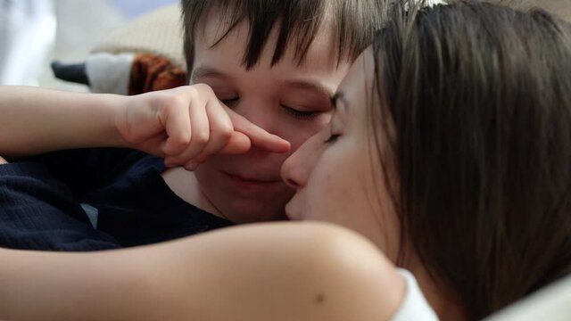 Young boy pokes mothers nose as she tries to take an afternoon nap