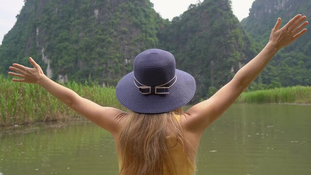 A young woman on a boat having a river trip among rocks in Ninh Binh, a tourist destination in northern Vietnam. Travel to Vietnam concept