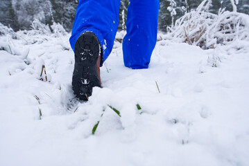 man hiking in winter forest by snow in hiking shoes boots. Winter hiking.