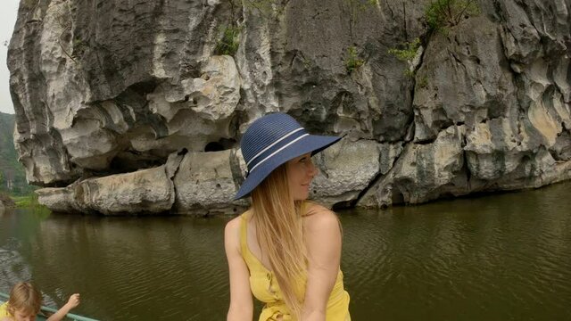 A young woman on a boat having a river trip among spectacular limestone rocks in Ninh Binh, a tourist destination in northern Vietnam. Travel to Vietnam concept