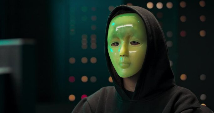 Masked Hacker is Using Computer for Organizing Massive Data Breach Attack on Corporate Servers. They're in Underground Secret Location. Masked Hacktivist Organizes Massive Data Breach Attack on
