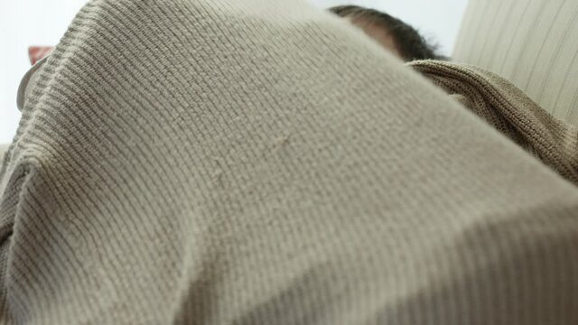 Mother and young son cuddle up on couch for afternoon nap - close up on faces