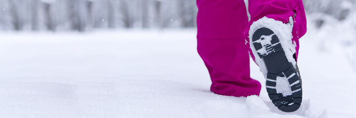 women hiking in winter forest by snow in hiking shoes boots. Winter hiking.