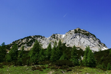 high rocky mountain and blue sky with a plane