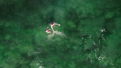 people swim in emerald clear water, rest of two girls