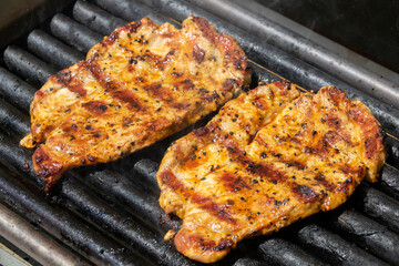 Grilling pork steaks. Delicious juicy meat steaks cooking on the grill.