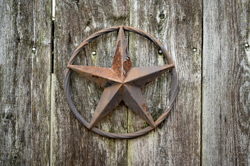 a rusted start emblem hanging on an old wooden fence