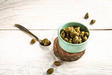 Marinated capers in a ceramic bowl. Edible flower buds of Capparis spinosa, caper bush or Flinders rose on a light background