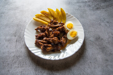 Continental delicacy chicken wings and potato wedges on a plate.