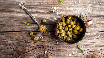 pickled capers on a dark wooden background. Edible flower buds of Capparis spinosa, caper bush or Flinders rose. Delicious ingredients for cooking