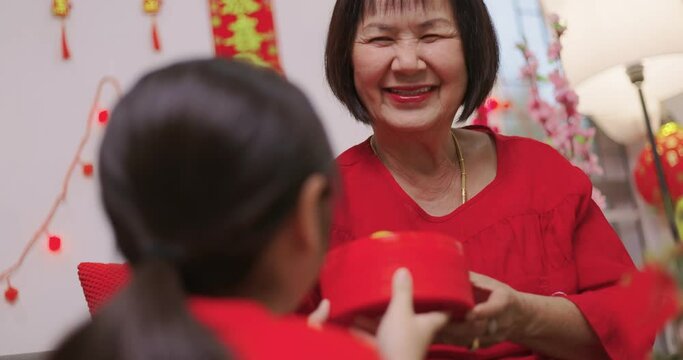 Happy Asian Girl Giving Her Grandmother Orange for Chinese New Year Blessing Gift.