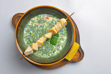 Cold soup okroshka served in a ceramic plate over white background. Traditional dish okroshka.