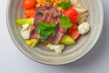 Juicy steak cut and served in a bowl with cut vegetables and feta cheese. Delicious Georgian dish.