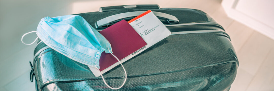 Travel during covid-19 with surgical face mask and tourist luggage panoramic banner. Plane ticket with passport.