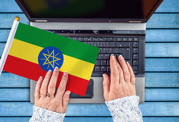 woman hands and flag of Ethiopia on computer, laptop keyboard 