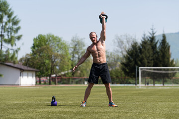 Muscular Man Exercising With Kettle-bell Outdoor