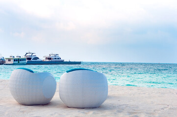 Modern white rattan furniture. White sand beach and turquoise ocean palm leaves. Relaxing sea landscape