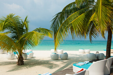  White sand beach and turquoise ocean palm leaves and modern white rattan furniture. Relaxing sea landscape