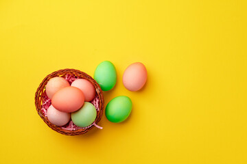 Decorative nest with colorful Easter eggs on yellow background