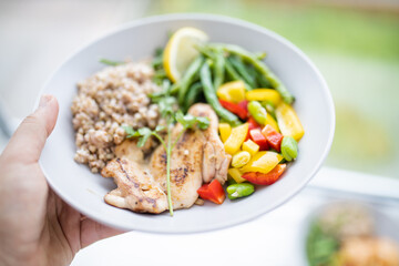 Hand holding a chicken and buckwheat dish with green beans