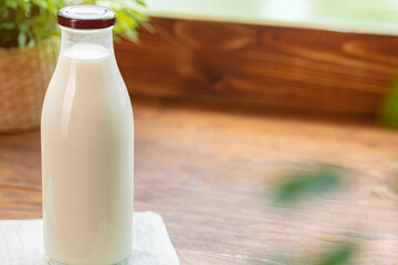 Glass bottle of milk on old wooden background