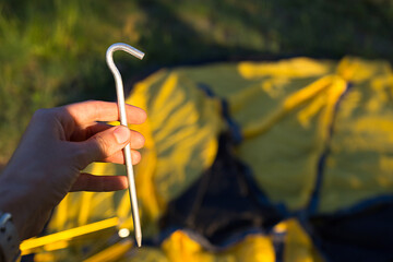 Aluminum stakes for the installation of a tourist yellow tent in the hand close-up. Lightweight...