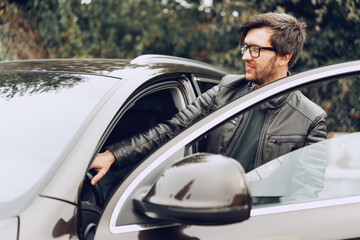 Fototapeta na wymiar Stylish man in glasses sits in a car