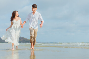 Love young couple holding hands and running on the beach. Holiday and vocation concept.