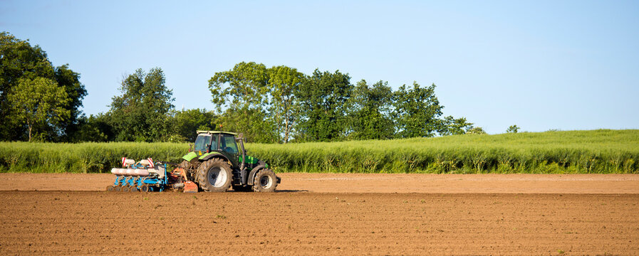 Tracteur au champ en train de labourer la terre au printemps.