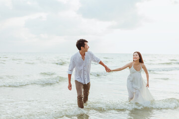 Fototapeta na wymiar Love young couple holding hands and running on the beach. Holiday and vocation concept.