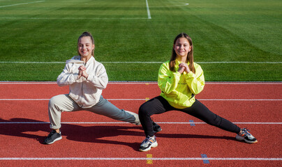 Balance your life. kids in sportswear stretching. children do exercise on track. healthy childhood. workout on fresh air outdoor. confident runner. flexible body. teen girls warming up on stadium