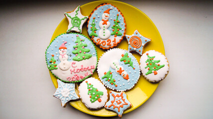 Gingerbread cookies with colorful festive icing on a yellow plate.
