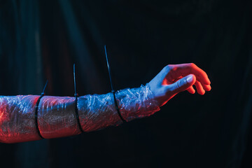 Man slavery. Human trafficking. Forced labour. Powerless male arm wrapped in polyethylene film...