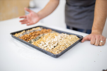 Man at a white table with a black tray of nuts and seeds