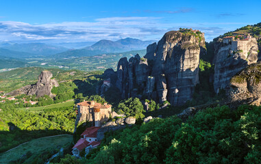 Morning view of Moni Agias Varvaras Roussanou in morning, Meteora, Greece and Varlaam monastery, rocks and valley. Rich foliage. UNESCO World Heritage