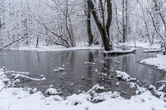 Winter scene with a frozen river in the woodland at Rowley in Burnley, Lancashire.  The snow and ice resting nicely on the tree branches and gives a very cold and wintery feeling to the image.