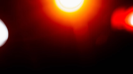 Bokeh light. Defocused sun rays. Lens flare. Blur glow. Red orange light leak flecks on black...
