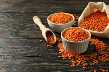 Bag, scoop and bowls with red legumes on wooden background