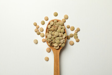 Wooden spoon with legumes on white background, close up