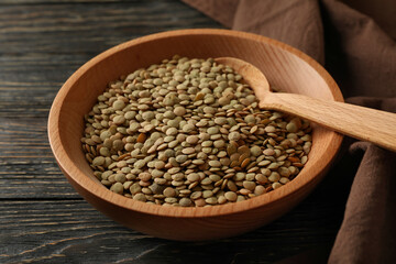 Kitchen towel, bowl with legumes and spoon on wooden background