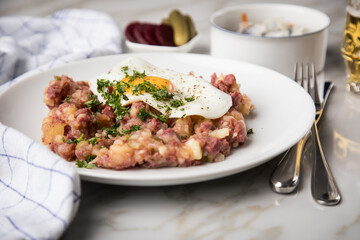 Norddeutscher Hamburger Labskaus mit Rindfleisch Corned Beef, Rote Beete, Kartoffeln, Saure Gurken, Spiegelei, Rollmops und Bier auf Marmor